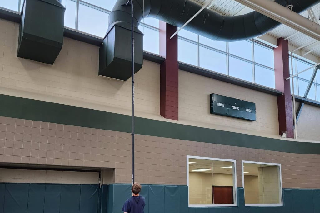 Technician performing high dusting and exterior cleaning for hard-to-reach surfaces